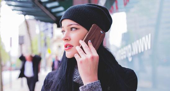 A woman holds a phone to her ear while on a call.