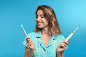 An image of a woman holding a tooth brush and an electric tooth brush