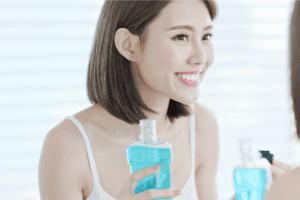 A woman holds and uses mouthwash to clean her teeth