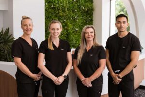 A group of dental professionals in a clinic, wearing white coats and masks, working together to provide dental care.